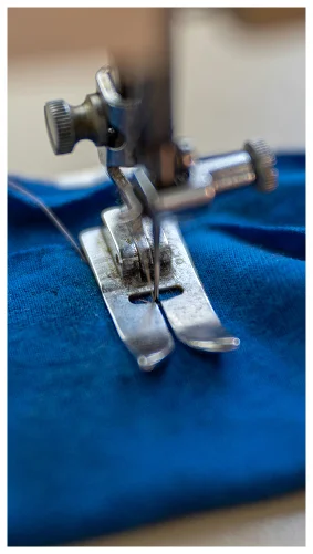 Close-up of sewing machine needle stitching blue fabric in a tailoring workshop